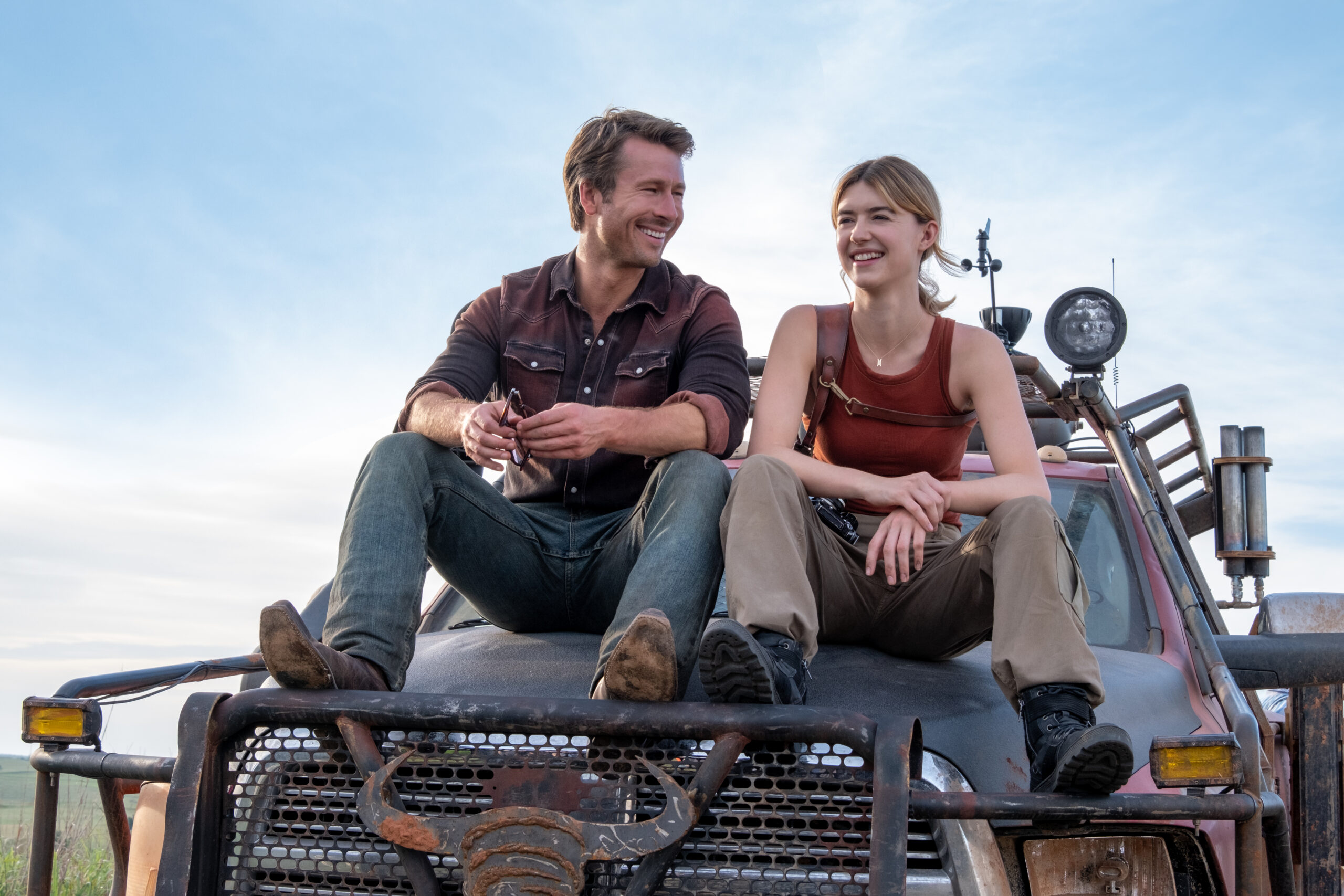 Actors Glen Powell and Daisy Edgar-Jones sit atop tornado-chasing vehicle.